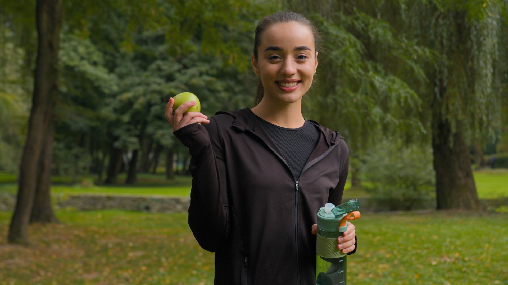 Sport woman Caucasian female thirsty drinking water health care refreshment in nature park morning workout outdoors smiling girl drink protein supply vitamins healthy nutrition diet fresh green apple
